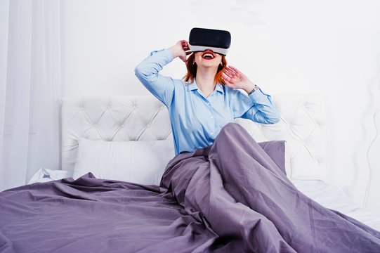 Red haired girl in bed with vr glasses at studio room.
