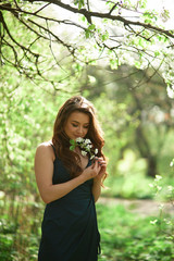 The charming lady stands in the park and keeps flowers