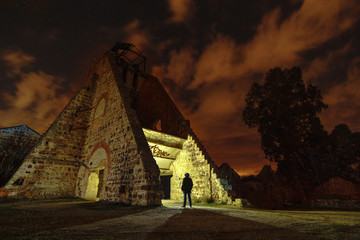 mysterious night scene of man backlit at night in an abandoned mine under a starry sky