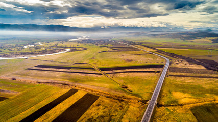 Aerial view of the hills and Carpathian mountains on a sunny spring day with clouds shadows on the ground