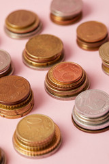 close-up shot of stacks of coins from different countries on pink