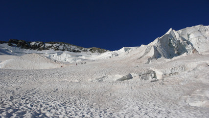 mountain climbers on a steep glacier on their way to a high alpine summit early in the mornin