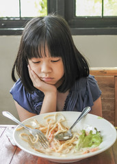 Unhappy Asian girl kid getting bored of food with appetite loss, no hungry habit, eating disorder