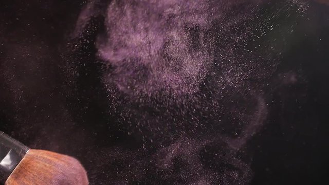 Powderbrush on black background with pink powder
