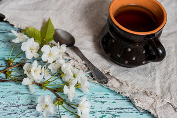 Obraz na płótnie Canvas Tea cup on the blue background with the spring blossom branch, spring flowers