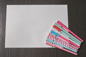 White blank sheet of paper and colored felt-tips on wooden table