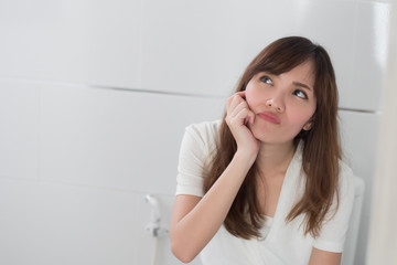 upset woman in toilet by diarrhea, constipation, hemorrhoids, piles; portrait of woman hard pushing in toilet or wc from diarrhea, constipation, food poisoning, hemorrhoids; asian adult woman model