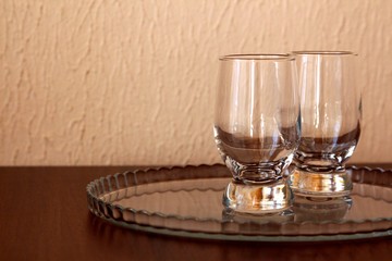 two empty glasses on clear tray on brown surface with place for text