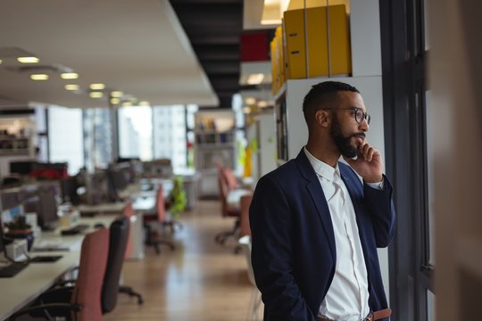Businessman talking on smartphone while standing in office