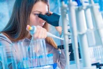  laboratory assistant with a pipette and a microscope in the laboratory
