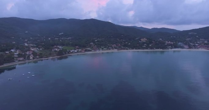 Aerial, island coast with beautiful calm sea in the evening and overcast sky