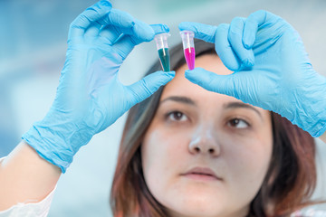 Female medical worker compares test tubes with biological samples
