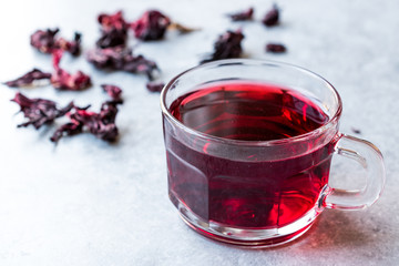 Red Hot Hibiscus Tea in a Glass Mug with Dry Hibiscus Tea Leaves.