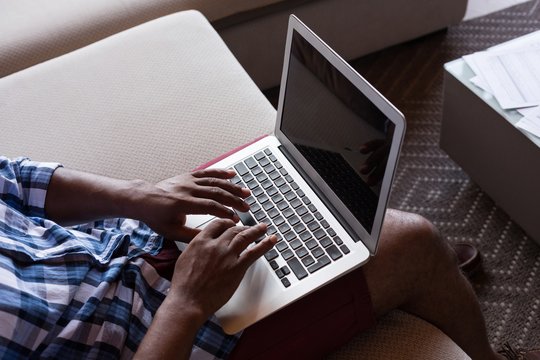 Senior man sitting on sofa while using laptop