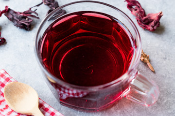 Red Hot Hibiscus Tea in a Glass Mug with Dry Hibiscus Tea Leaves.