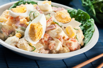 Delicious potato salad with ham, egg and cucumber
