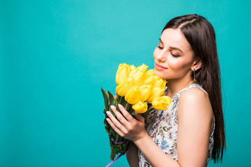 portrait of smiling woman with bouquet of yellow tulips in hands isolated on green background
