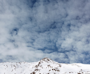 Fototapeta na wymiar Snowy mountain peak on the background of cloudy sky