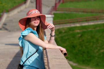 redhead ginger girl dressed in сoral color hat and blue dress summer portrait