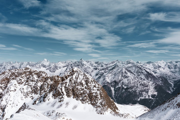 Fototapeta na wymiar Alpine panoramic Alpine landscape. Mountain peaks in the snow on a background cloudy sky