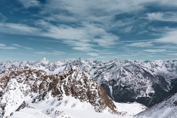 Fototapeta premium Alpine panoramic Alpine landscape. Mountain peaks in the snow on a background cloudy sky
