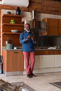 Smiling man using digital tablet in kitchen at home