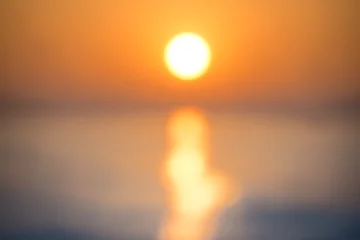 Fotobehang Zonsondergang aan zee Blur abstract sunset over sea with sun, waves and shining light on the water- blurred background