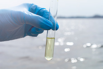 Hand in glove collects water in a test tube. Concept - water purity analysis, ecology. Water...