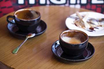 Two cups of hot chocolate or coffee cappuccino on the table in cafe, close up,remains of breakfast.