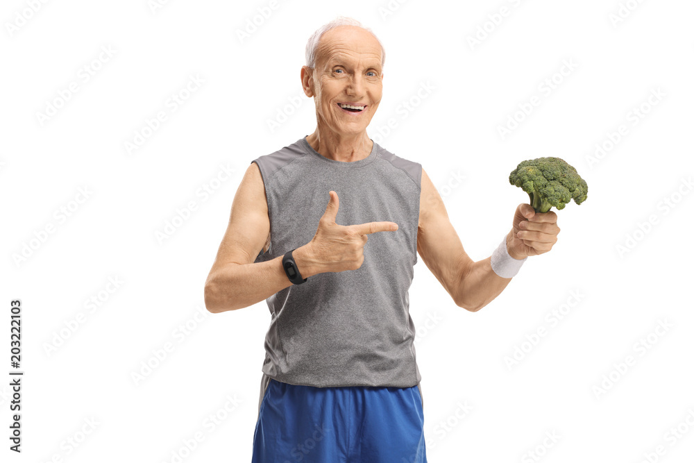 Wall mural Senior in sportswear holding broccoli and pointing