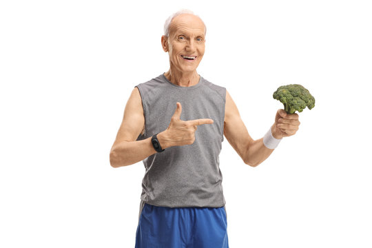 Senior in sportswear holding broccoli and pointing