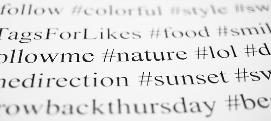 Closeup of typed popular hashtags. Words on the paper sheet. Abstract concept of social media, communication, social networking, digital society, and internet.
