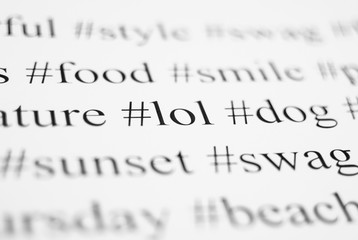 Fototapeta premium Closeup of typed popular hashtags. Words on the paper sheet. Abstract concept of social media, communication, social networking, digital society, and internet.