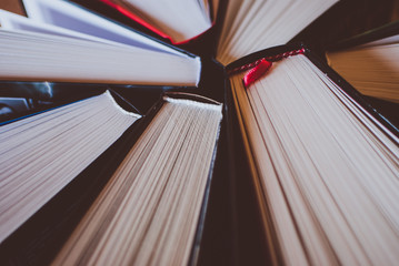 Pile of open books on the wooden table. Closeup of pages. Abstract concept of knowledge, education, learning, and literature.