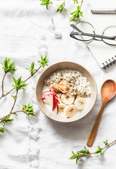 Vegetarian gluten free breakfast - quinoa, coconut milk, banana, apple, peanut butter bowl on light background, top view. Diet plan breakfast or snack and empty clean notebook. Flat lay
