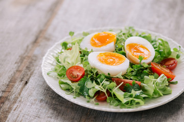 High Angle View of a Nutritious Vegetable Salad with Boiled Egg Slices, Served on a White Plate on Top of a Wooden Table