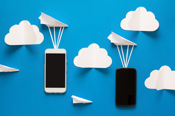 Data transfer concept. Message passing. Two mobile smartphones and paper airpaplanes on blue...