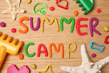 Text SUMMER CAMP made with play dough on wooden background, top view