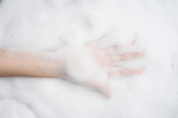 Fototapeta premium Hand female with soft foam bubble from soap or shampoo washing on top view