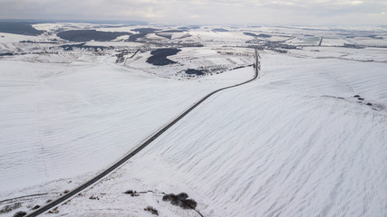 Obraz premium View from the air on the winter road in the field on which cars are going