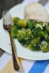 Useful dish of Brussels sprouts is on a plate, next to a fork and a piece of chicken
