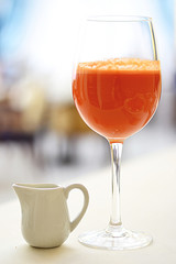 Delicious freshly squeezed carrot juice in a glass that stands on the table, the background is very blurred
