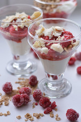 Yogurt muesli is beautifully decorated in a glass glass decorated with cereal and frozen raspberries