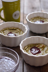 Dessert matcha mousse in a white plate drizzled with jam lies on a wooden table