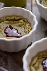 Dessert matcha mousse in a white plate drizzled with jam lies on a wooden table