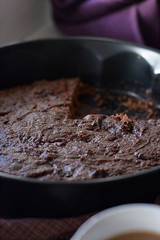 Chocolate cake from which the piece is cut lies in the form of baking.
