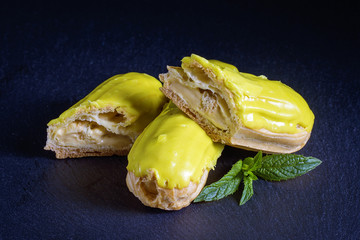 Pistachio eclair in glaze on black background, close up