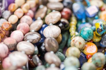 Macro shot of rhodochrosite stone, jasper, glass, hrizokola stones. Gemstone bracelets and necklaces in a row. Healing, powerful energy for crystal therapy treatments and reiki. Esoteric background.