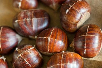 Chestnuts being prepared for baking with a knife-cut cross on top of each nut 