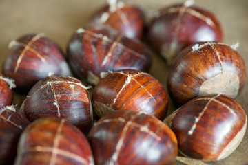 Chestnuts being prepared for baking with a knife-cut cross on top of each nut 